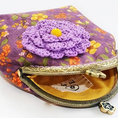 жіноча косметичка - гаманець своїми руками з щільної бавовни у фіолетовій гамі з малюнком - квітами. Косметичка з тканини прикрашена великою в'язаною гачком квіткою. Косметичка з фермуаром є сьогодні найбільш затребуваним аксесуаром! Вірна супутниця сучасної жінки - гаманець косметичка!