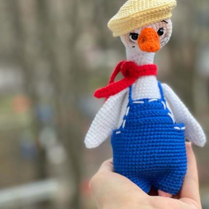 В’язана іграшка біле гусенятко в комбінезоні з кепкою