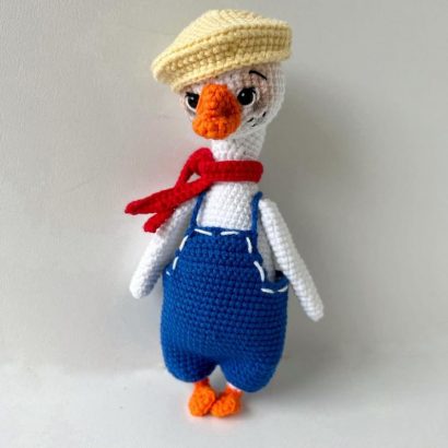 В’язана іграшка біле гусенятко в комбінезоні з шапочкою