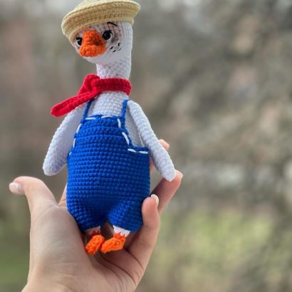 В’язана іграшка біле гусенятко в комбінезоні з кепкою