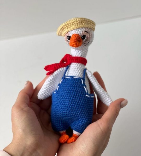 В’язана іграшка біле гусенятко в комбінезоні з кепкою