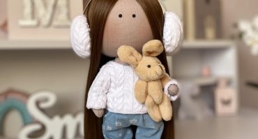 Казкова текстильна лялька у джинсах з принтом ромашок, в’язаному светрику та з м’якою іграшкою – ідеальний подарунок для модної маленької леді